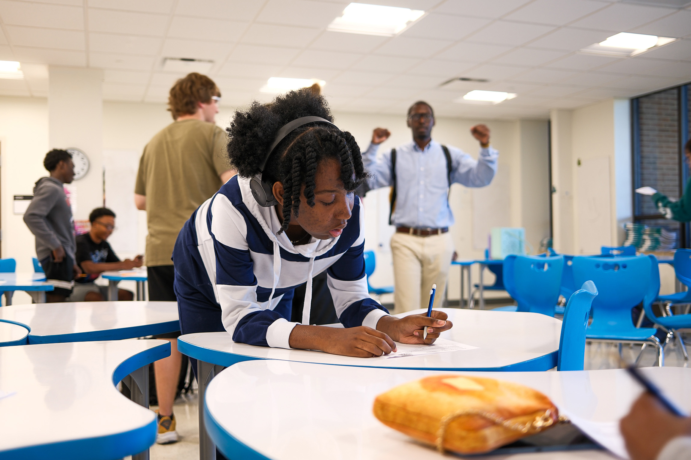 Student working at a table with a Program Director in the background
